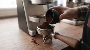 Pouring fresh coffee grounds into a portafilter.