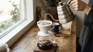 Demonstrating a stovetop gooseneck kettle for pour over brewing coffee into a ceramic cone dripper on a wooden bar.